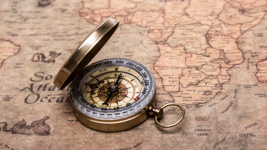 Vintage brass compass on antique world map showcasing detailed cartography and exploration Wallpaper