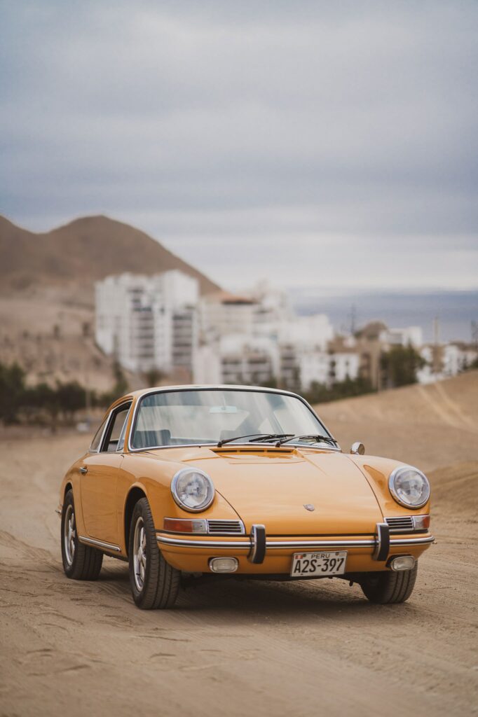 Vintage Car Wallpaper: Retro Design on Sandy Road with Scenic Background
