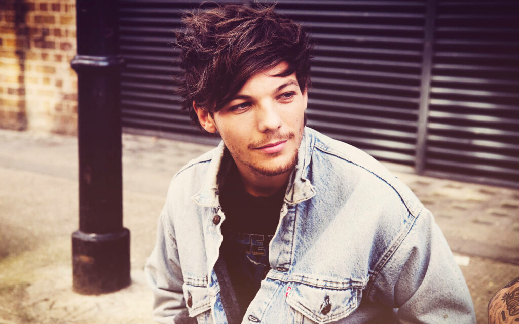 Retro Charm: Louis Tomlinson Exudes Cool in Denim Jacket Amidst Nature's Beauty Wallpaper