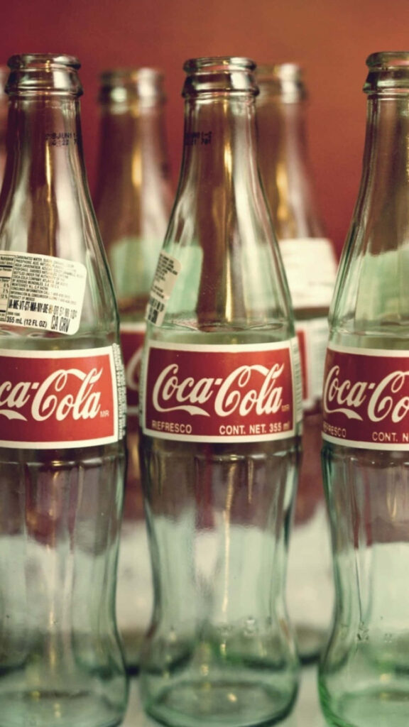 Close-up of vintage Coca-Cola glass bottles with iconic red and white logo nostalgic wallpaper