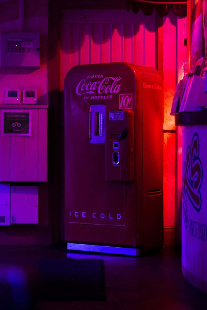 Vintage Coca-Cola vending machine under neon magenta and purple lights with classic retro branding Wallpaper