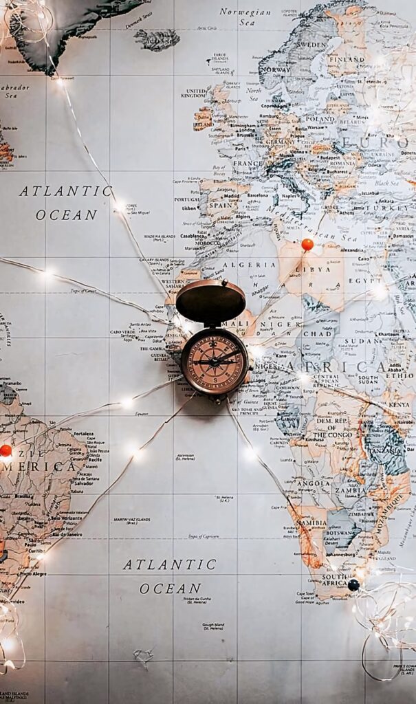 Vintage compass on detailed world map with warm string lights inspiring travel and adventure Wallpaper