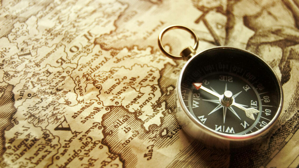 Vintage compass on sepia map wallpaper with detailed cartography evoking adventure and exploration