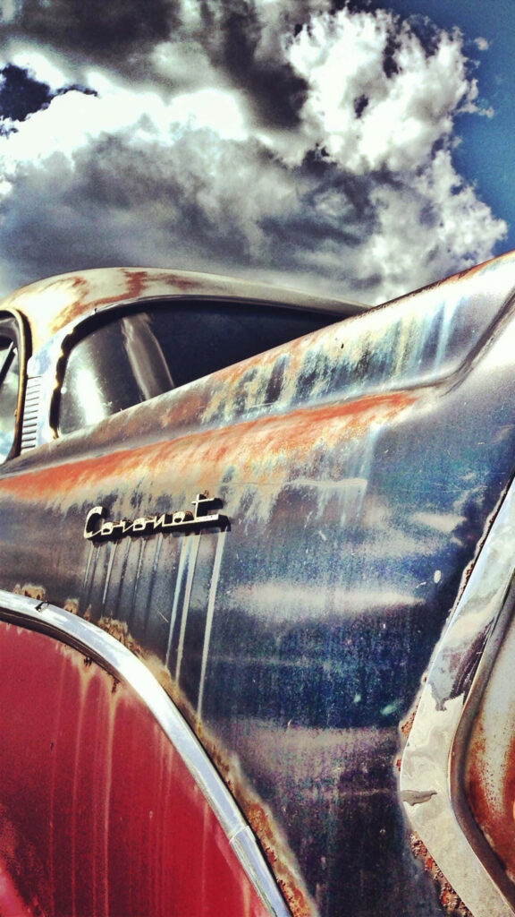 Vintage Dodge Coronet close-up with rusted textures and chrome details under dramatic sky wallpaper