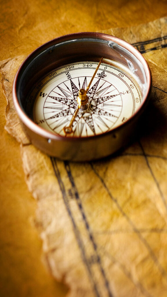 Nostalgic Nature's Guide: A Timeless Compass atop Weathered Parchment Wallpaper