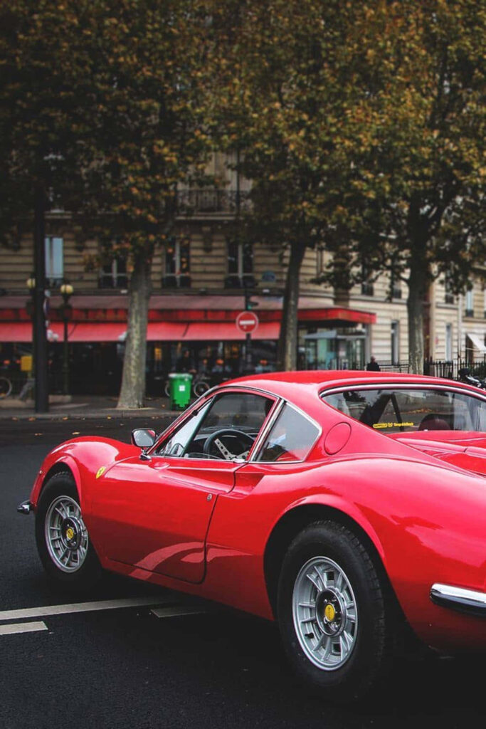 Vintage Ferrari Enchants Scenic Countryside with Striking Red Against Serene Blue Sky Wallpaper