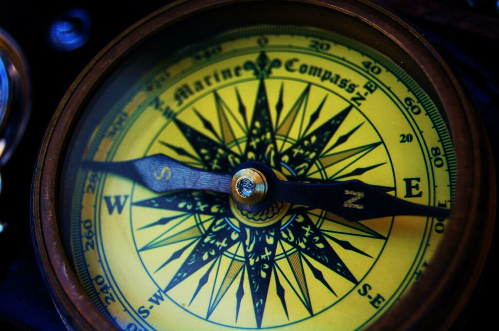 Close-up of vintage yellow marine compass with black markings highlighting navigation and exploration Wallpaper