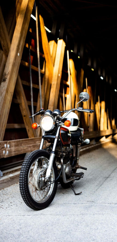 Vintage Motorcycle Under Rustic Bridge - Serene Wallpaper Background