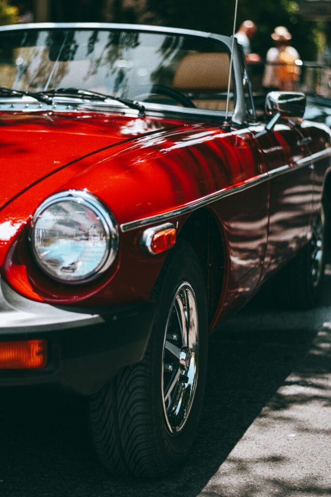 Vintage Red Convertible Car with Gleaming Highlights on Streetscape Wallpaper