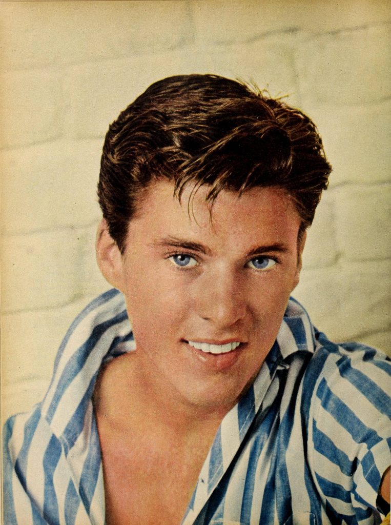 Vintage portrait of teen idol Ricky Nelson with blue eyes and striped shirt on brick wall background Wallpaper