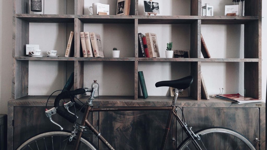 Vintage road bike by rustic dark wood bookshelf with books and succulents virtual background Wallpaper