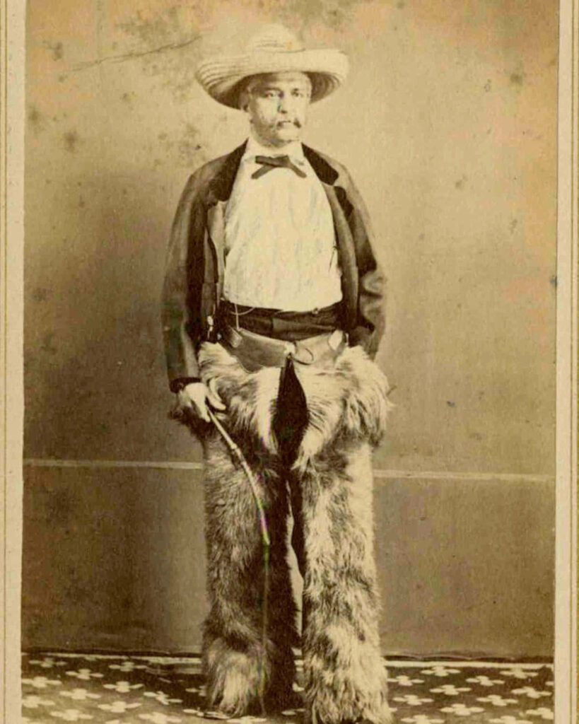 Vintage sepia wallpaper of cowboy in fur pants wide-brim hat and Western jacket Wild West background
