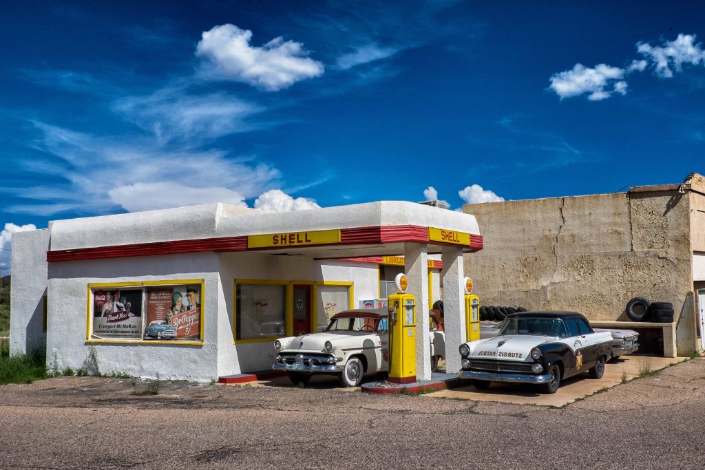 Vintage Shell gas station wallpaper with retro cars under a classic canopy on sunny day