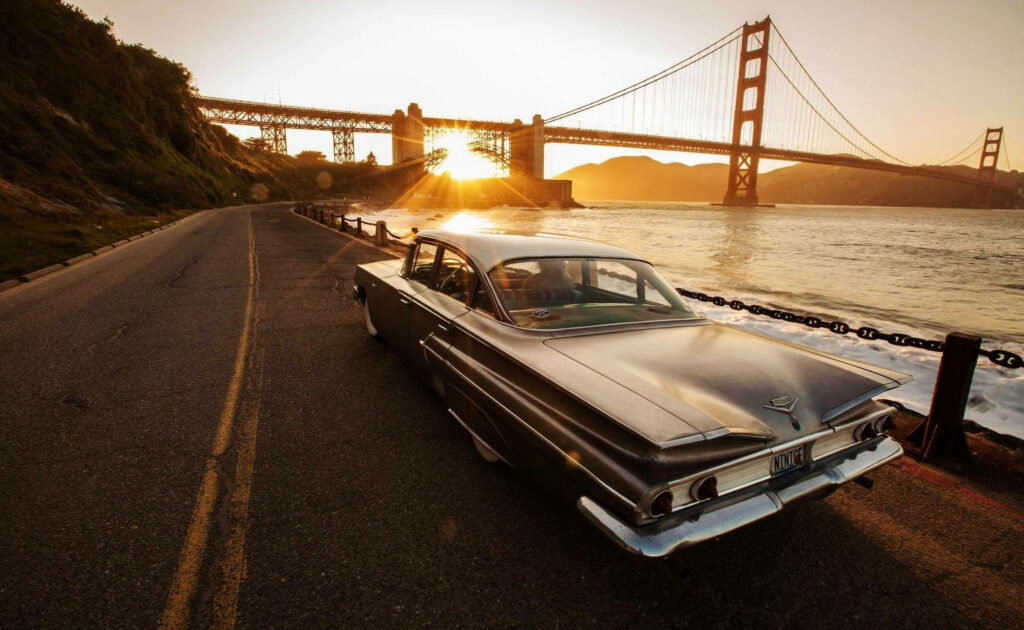 Nostalgic Drive: Chevrolet Impala Silhouetted against a Glowing Sunset Wallpaper