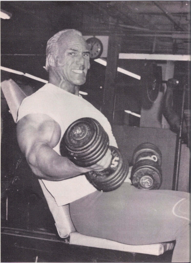 Vintage wallpaper of Superstar Billy Graham lifting heavy dumbbells showing strength in gym