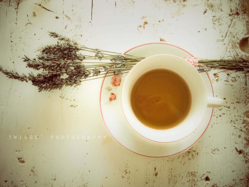 Delicate tea cup with warm tea on whitewashed wood beside dried lavender vintage scene Wallpaper