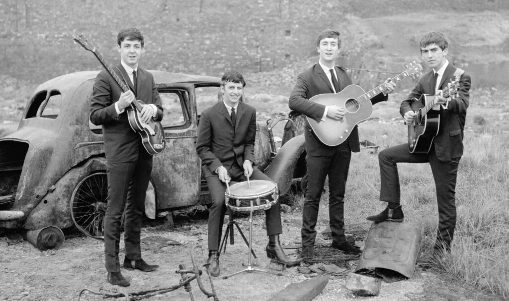 Vintage Beatles Wallpaper: Iconic Band with Instruments by Old Car