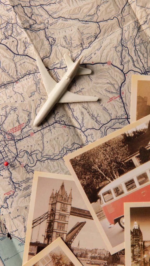 Vintage travel wallpaper with Lompoc map model airplane and nostalgic London postcards flat lay