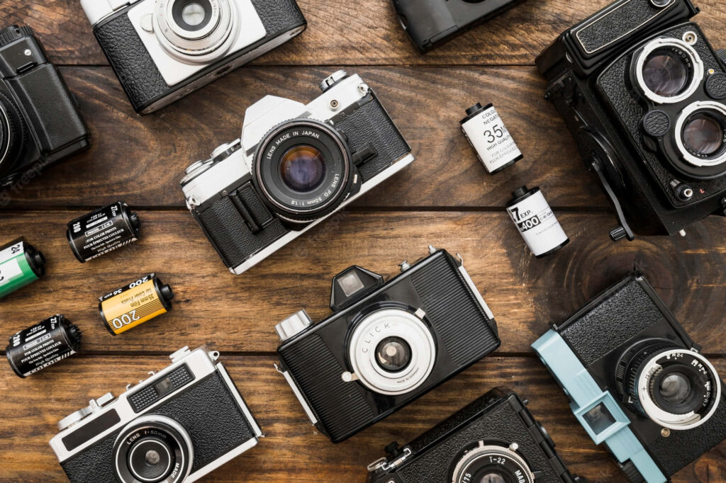 Capturing Timeless Memories: Vintage Camera Ensemble on Wooden Table Wallpaper