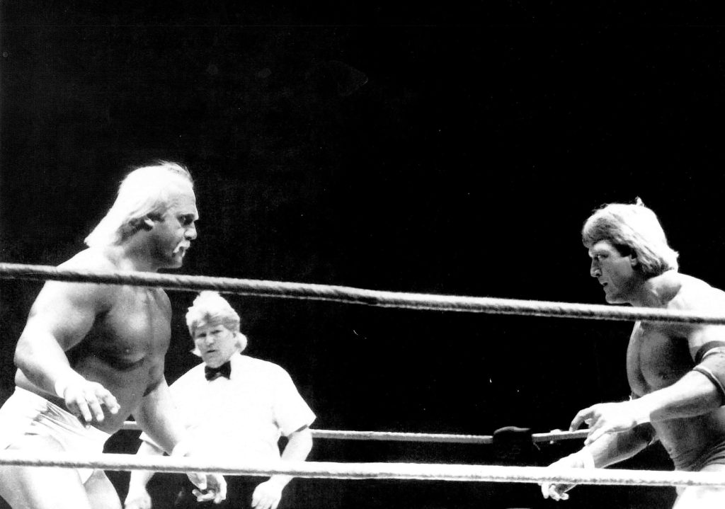 Black and white wallpaper of WWF legends Hulk Hogan and Paul Orndorff wrestling with referee in ring