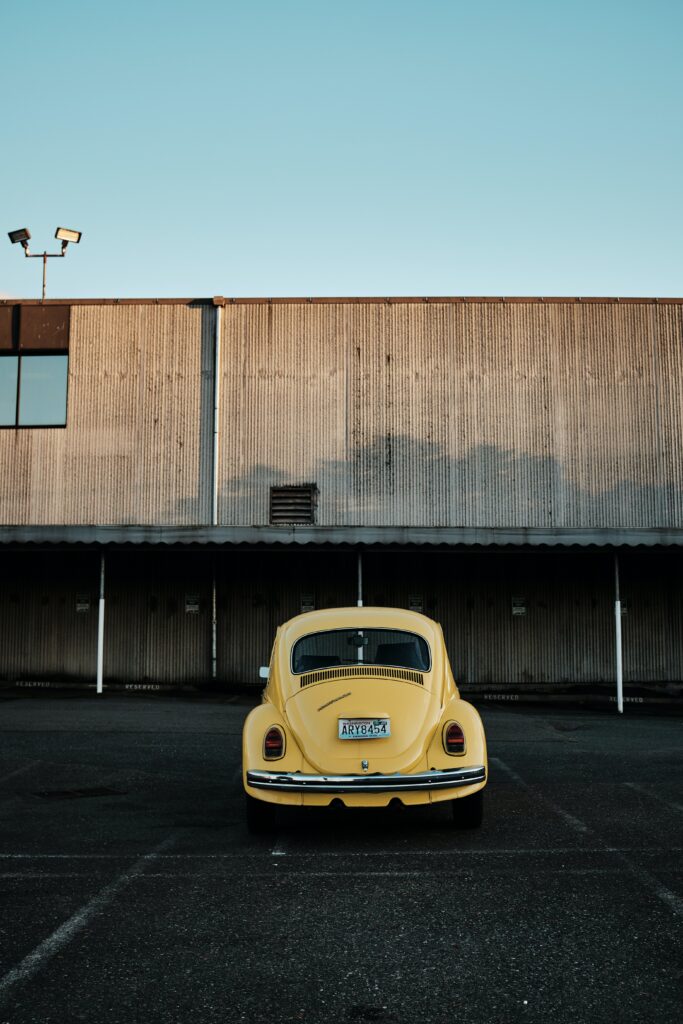 Vintage Yellow Car Against Industrial Backdrop - Retro Wallpaper
