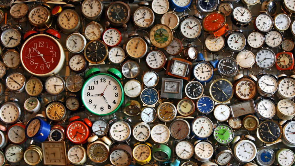 Colorful vintage and modern clocks wallpaper with overlapping timepieces creating textured depth