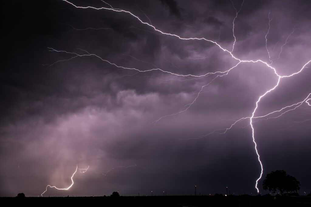 Violet lightning bolts burst through dense clouds lighting night sky in dramatic storm wallpaper