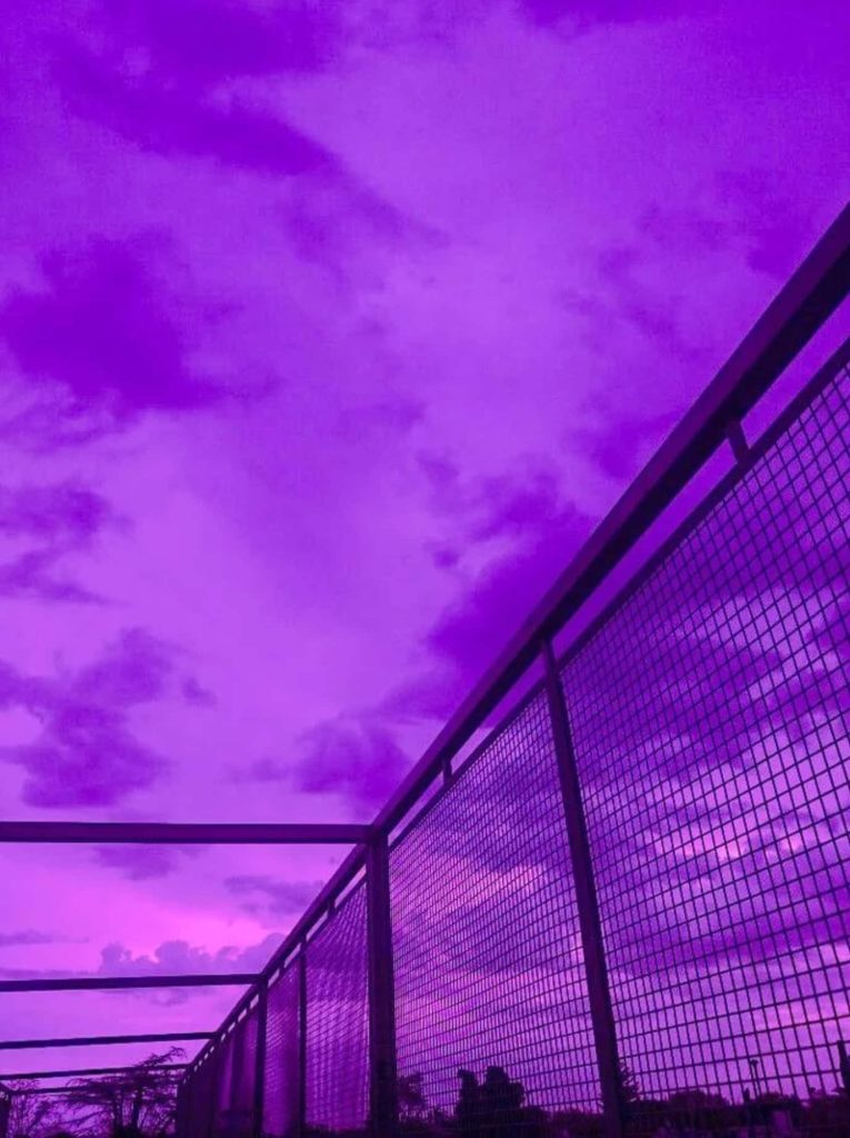 Violet cloudy sky view through metal railing vibrant moody urban aesthetic wallpaper background