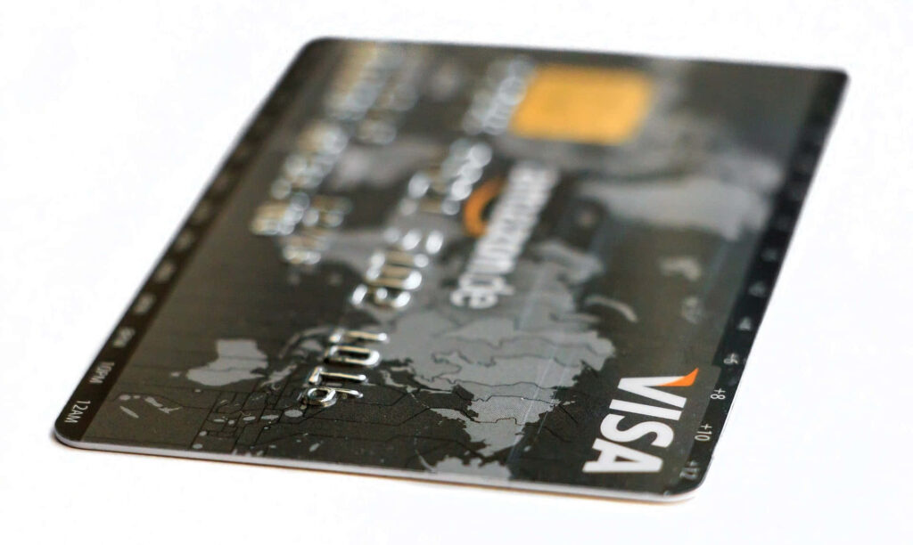 Visa credit card with gray black world map design on white surface symbolizing global spending Wallpaper