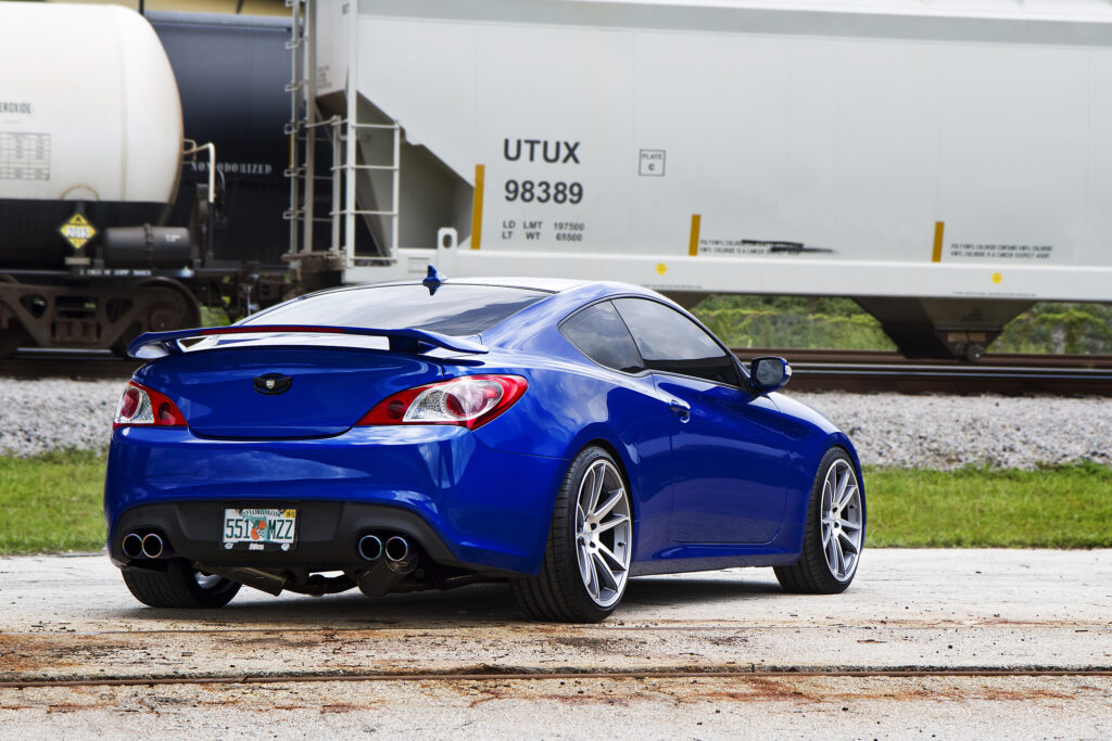 Vivid Blue Hyundai Genesis: Rear View in Urban Train Setting Wallpaper