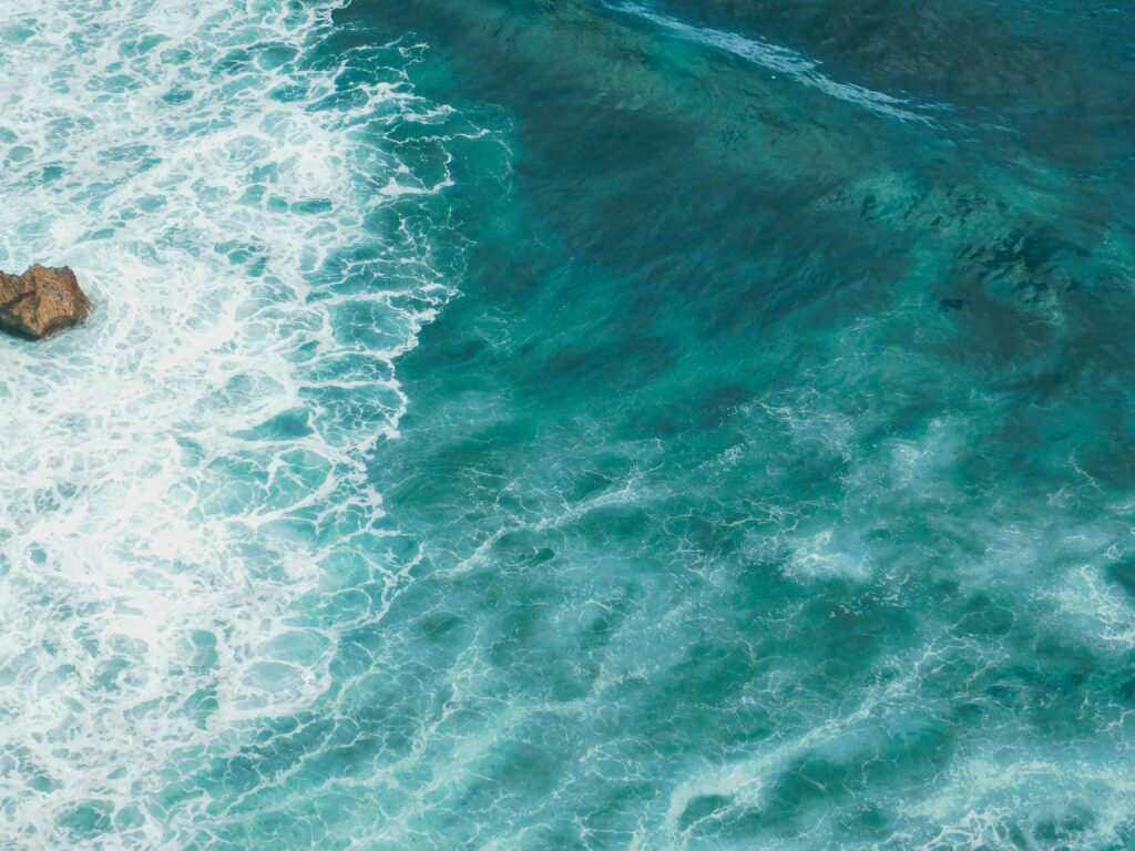 Vivid blue turquoise ocean wallpaper with rolling waves textured water surface background
