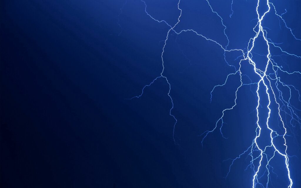 Vivid lightning bolts branching across deep blue sky storm wallpaper background with electric energy