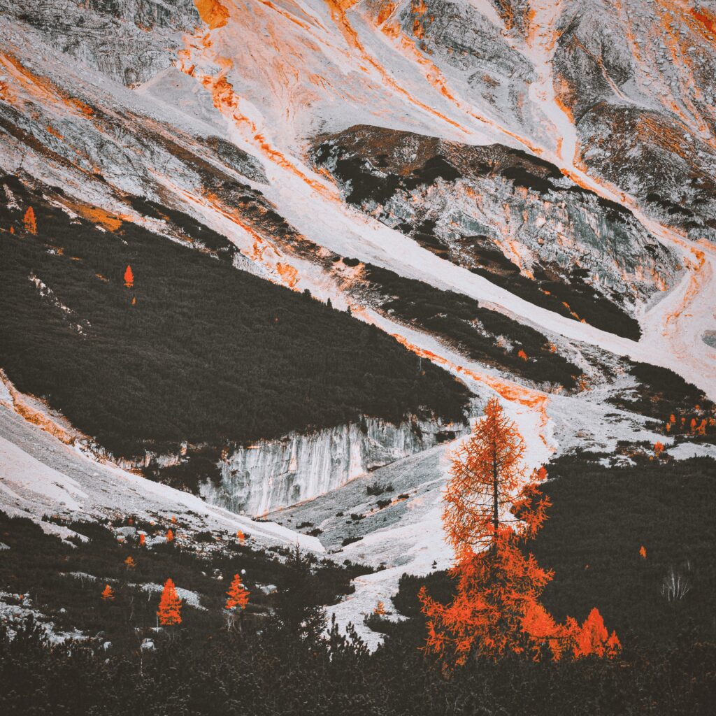 Rugged mountain landscape wallpaper with green trees and bright orange foliage vivid natural beauty