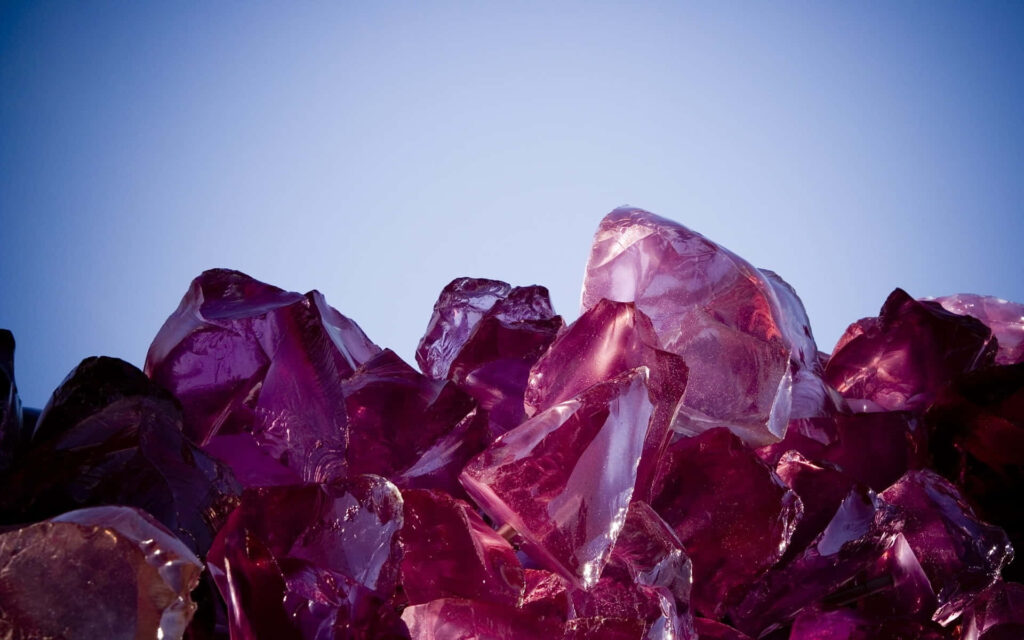 Purple gemstone crystals with jagged edges on soft gradient blue background wallpaper design