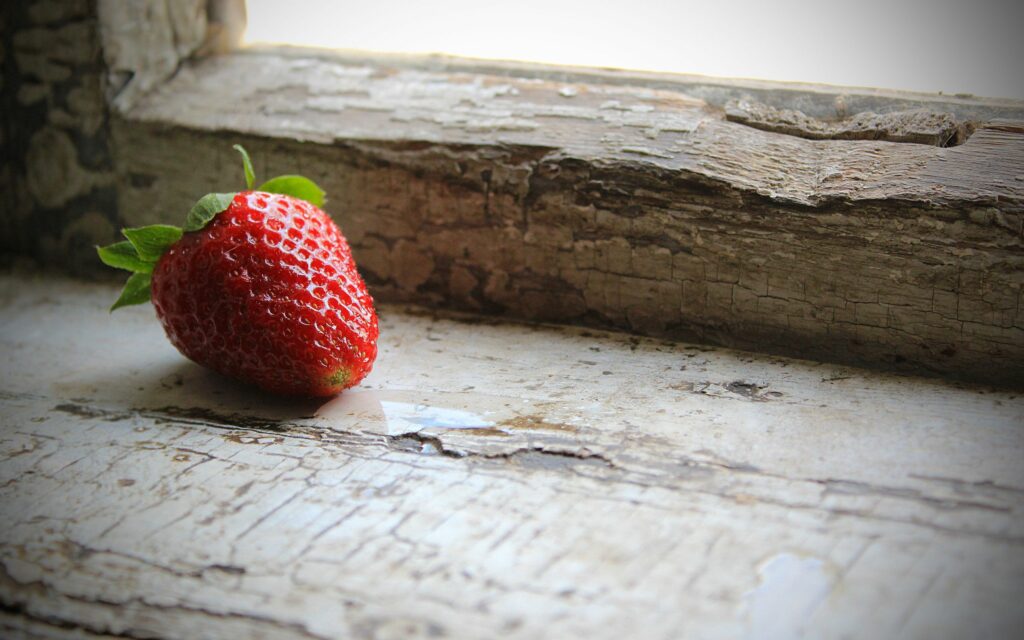 Vivid Red Strawberry on Weathered Windowsill - Wallpaper Background