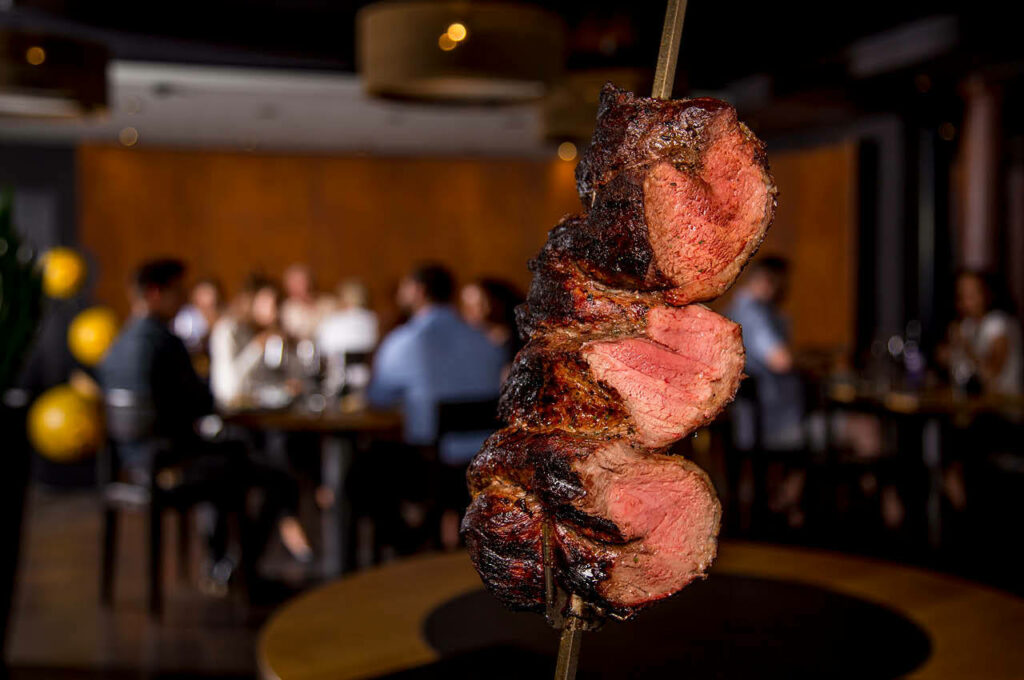 Vivid Wallpaper of Grilled Meat Skewers in Inviting Rio Churrasco