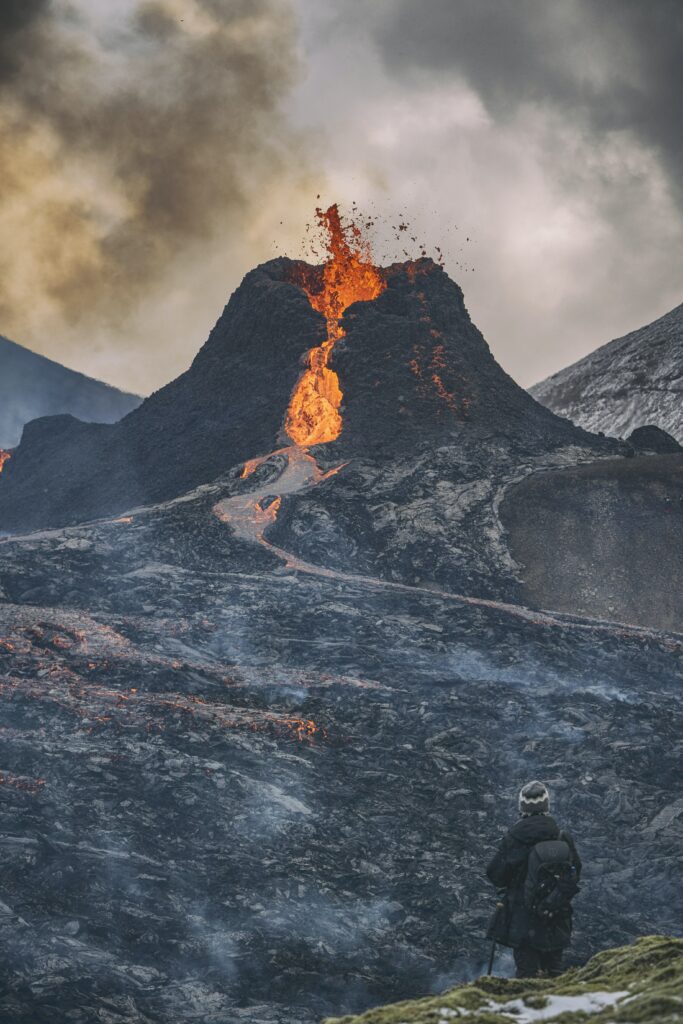 Volcanic eruption wallpaper molten lava flowing black slopes thick smoke cloudy sky observer view