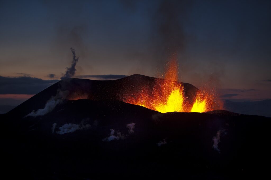 Nighttime volcano eruption with glowing lava fountains fiery bursts and billowing smoke wallpaper background