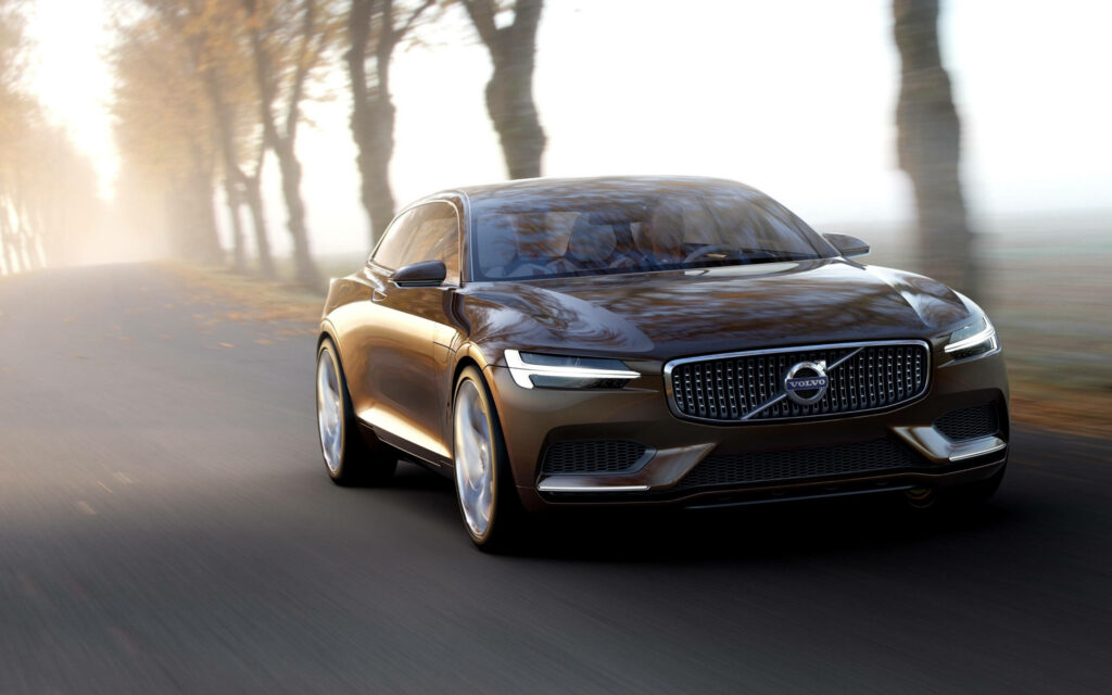 Volvo S90 luxury sedan driving on foggy tree-lined road showcasing sleek metallic design Wallpaper