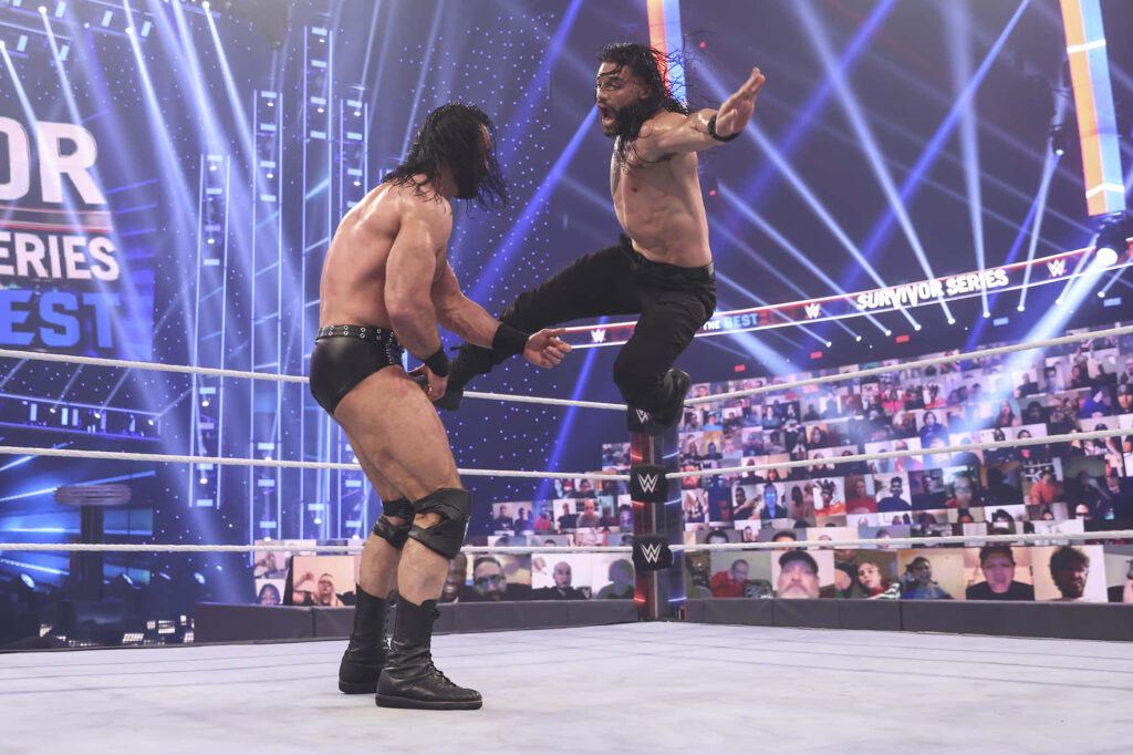 WWE Clash wallpaper with Drew McIntyre and Roman Reigns fighting under vibrant stadium lights