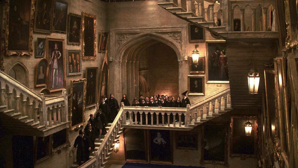 Magical Nostalgia: A Delightful Harry Potter Background - Young Students Marvel at the Grand Staircase's Aesthetic and Enchanting Paintings Wallpaper