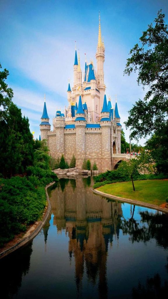 Walt Disney World Cinderella Castle reflected on calm lake with lush greenery wallpaper background