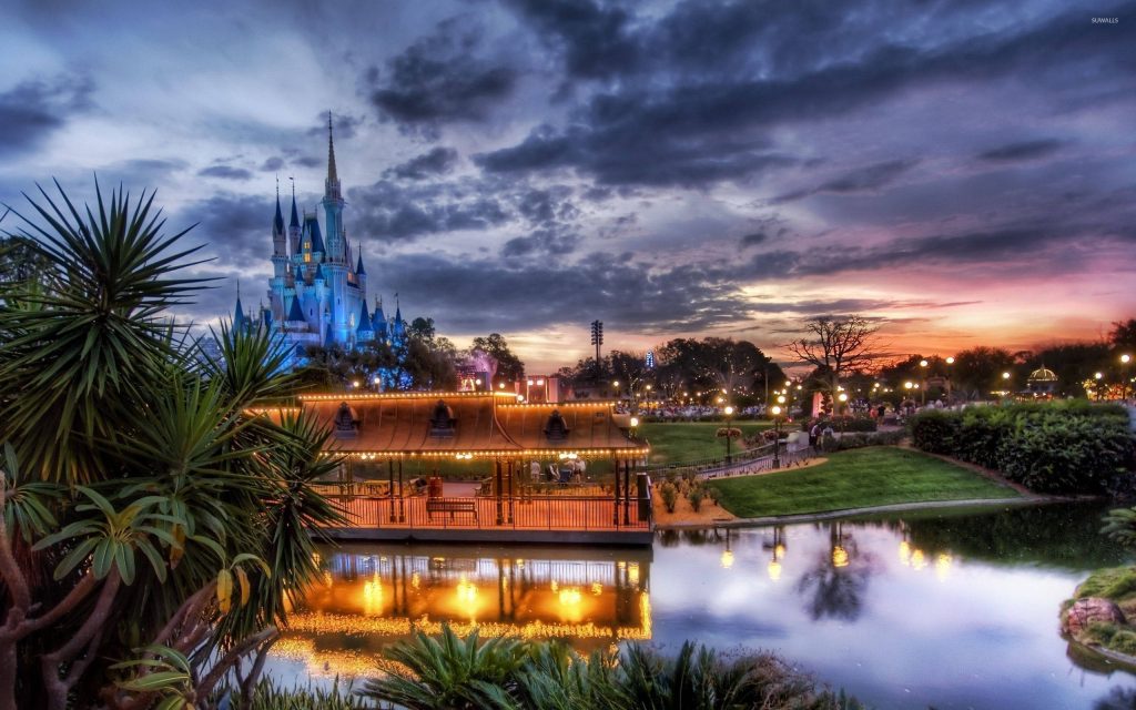 Walt Disney World Cinderella Castle glowing at sunset with waterfront and palm trees wallpaper