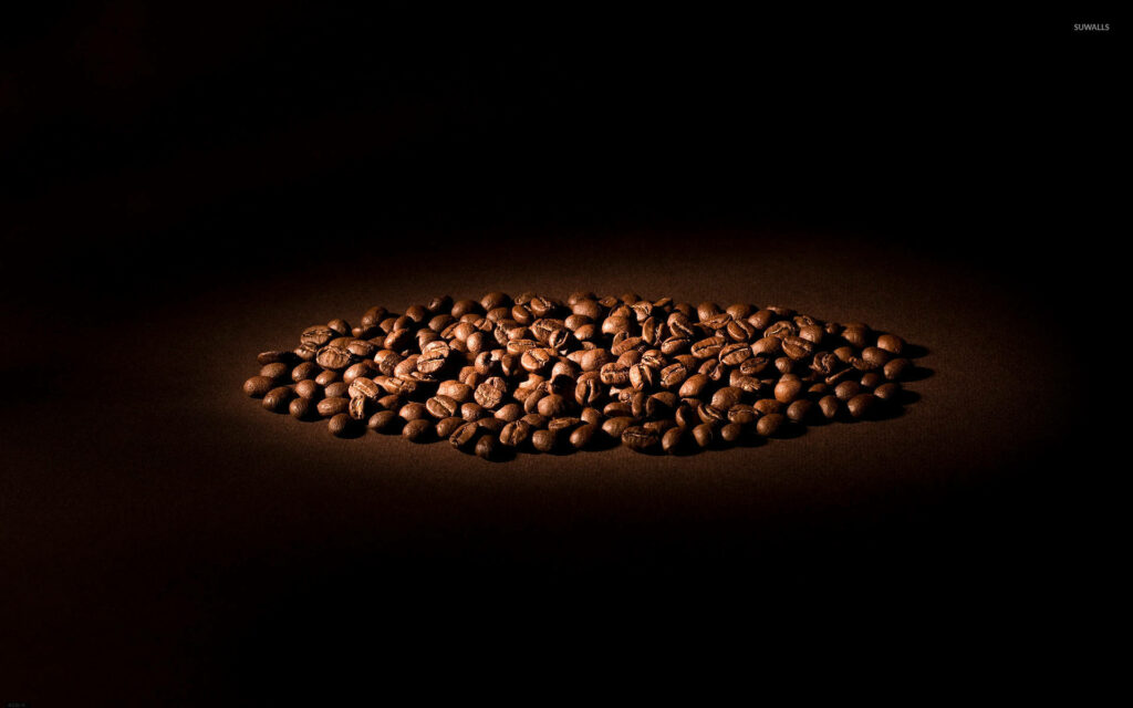 Roasted coffee beans pile highlighted by soft light on dark background warm inviting wallpaper