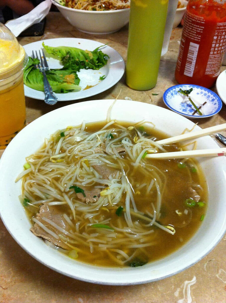 Warm Vietnamese Pho with Herbs & Chopsticks - Rustic Table Wallpaper