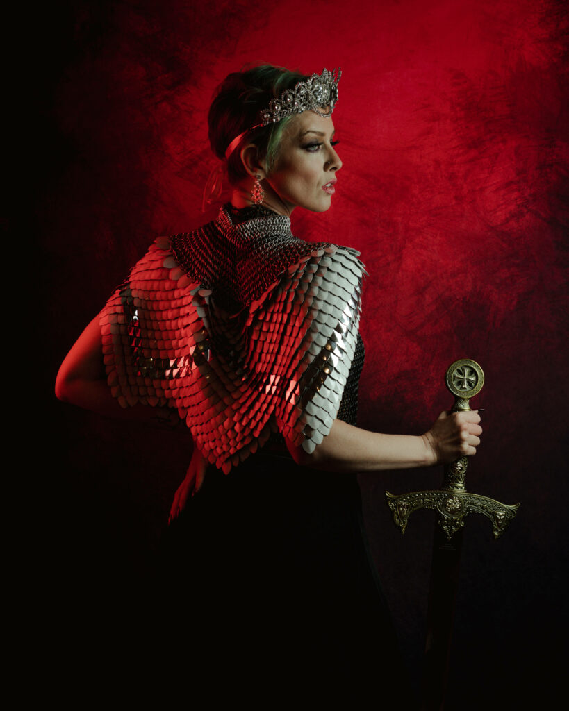 The Fierce Artistry of a Regal Enchantress: Graceful Blades Amidst a Vibrant Scarlet Tapestry Wallpaper