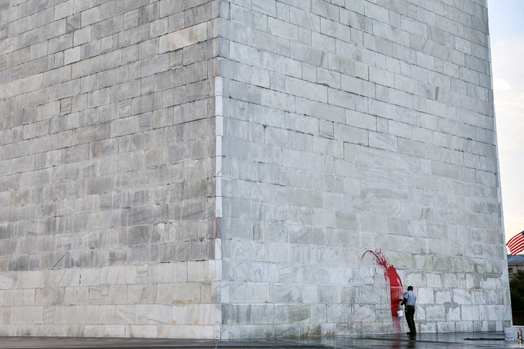 Worker removes red graffiti from Washington Monument white marble wall showing preservation efforts Wallpaper