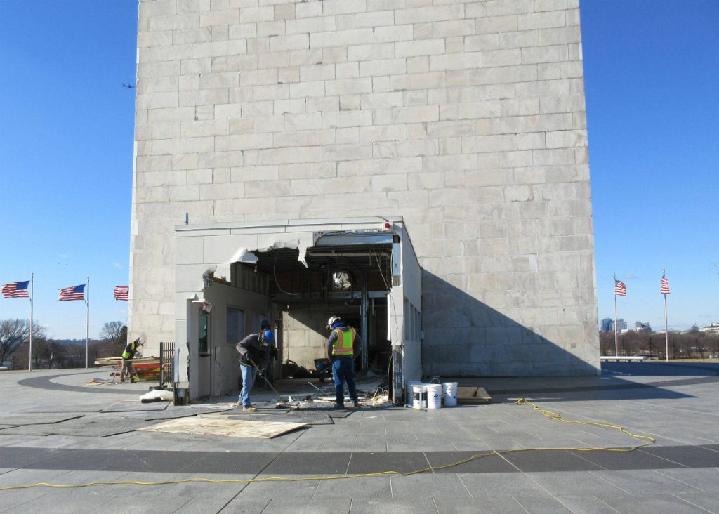 Construction workers renovating the Washington Monument entrance under a clear blue sky Wallpaper