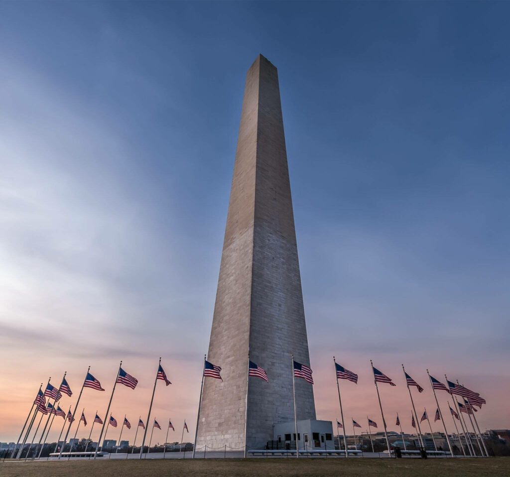 Washington Monument sunset ground view with waving American flags patriotic wallpaper background