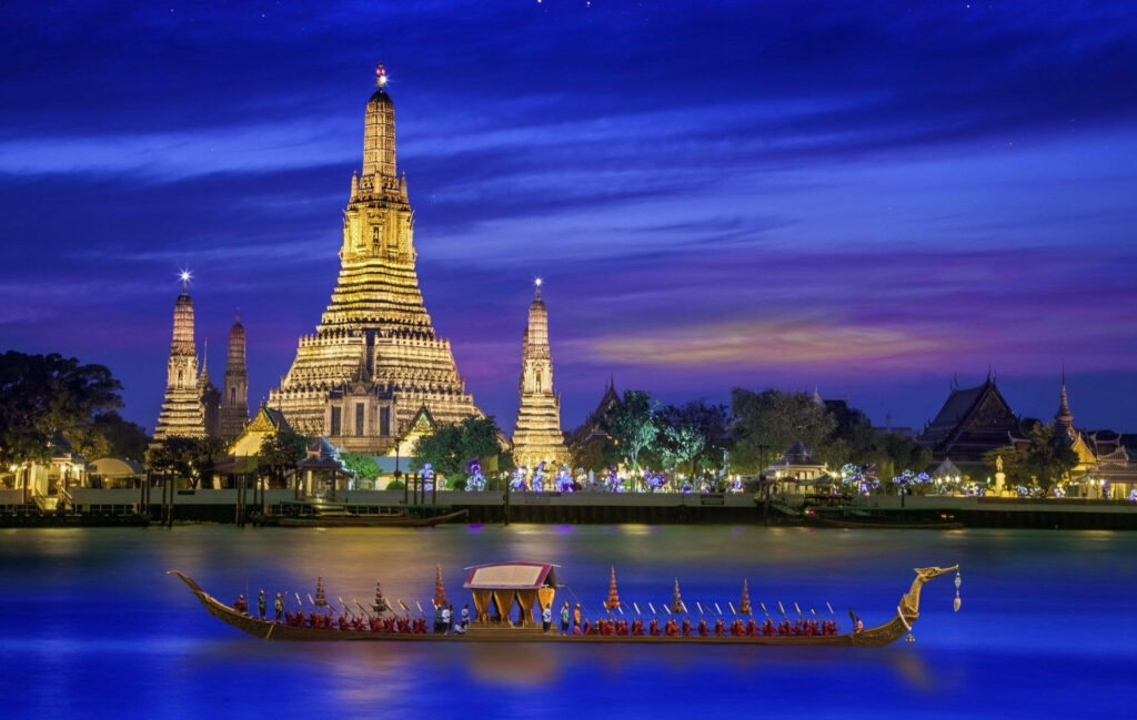 Wat Arun temple illuminated at night Bangkok with longtail boat on calm river twilight sky wallpaper